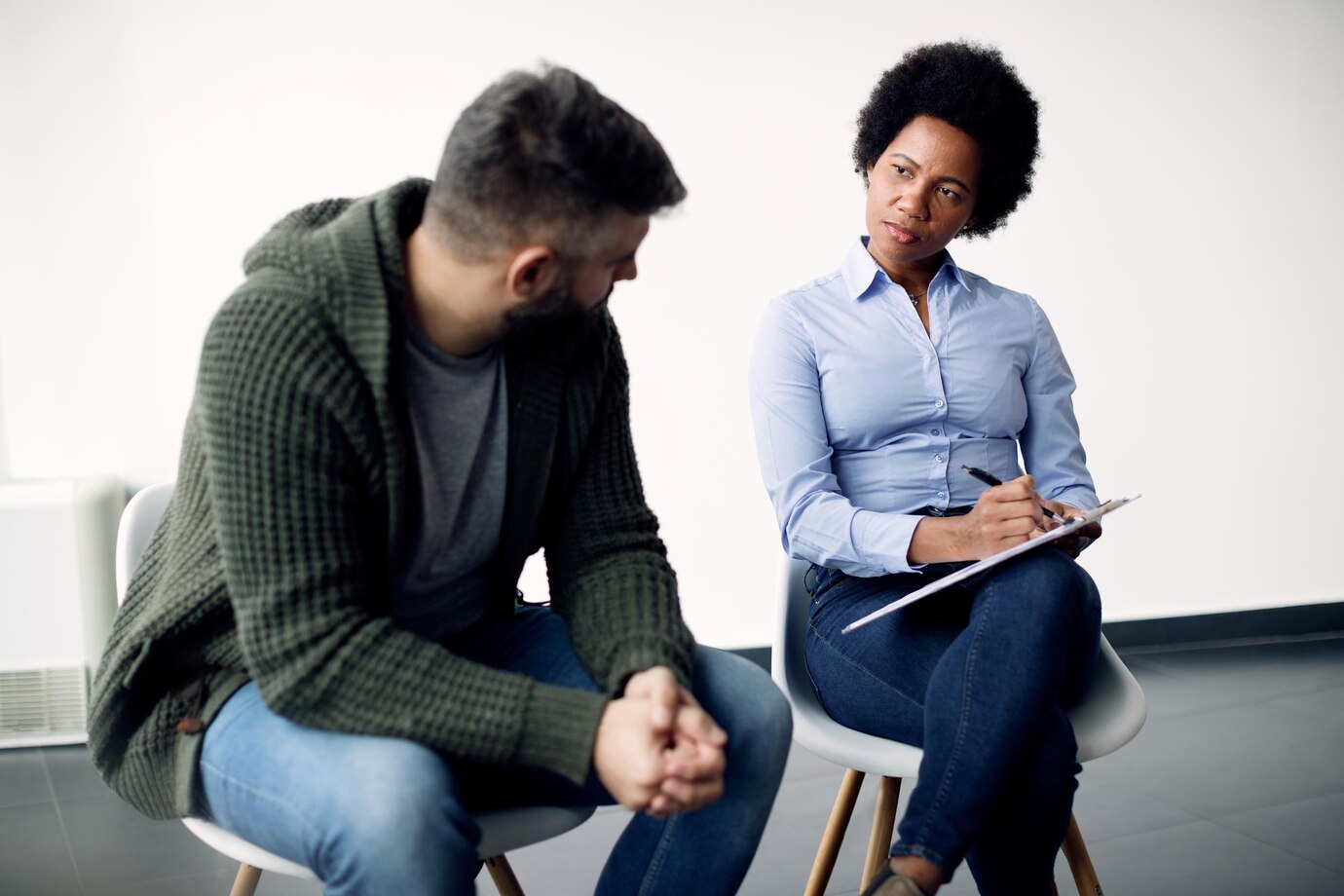 black-female-psychotherapist-taking-notes-while-talking-man-counselling_637285-9963